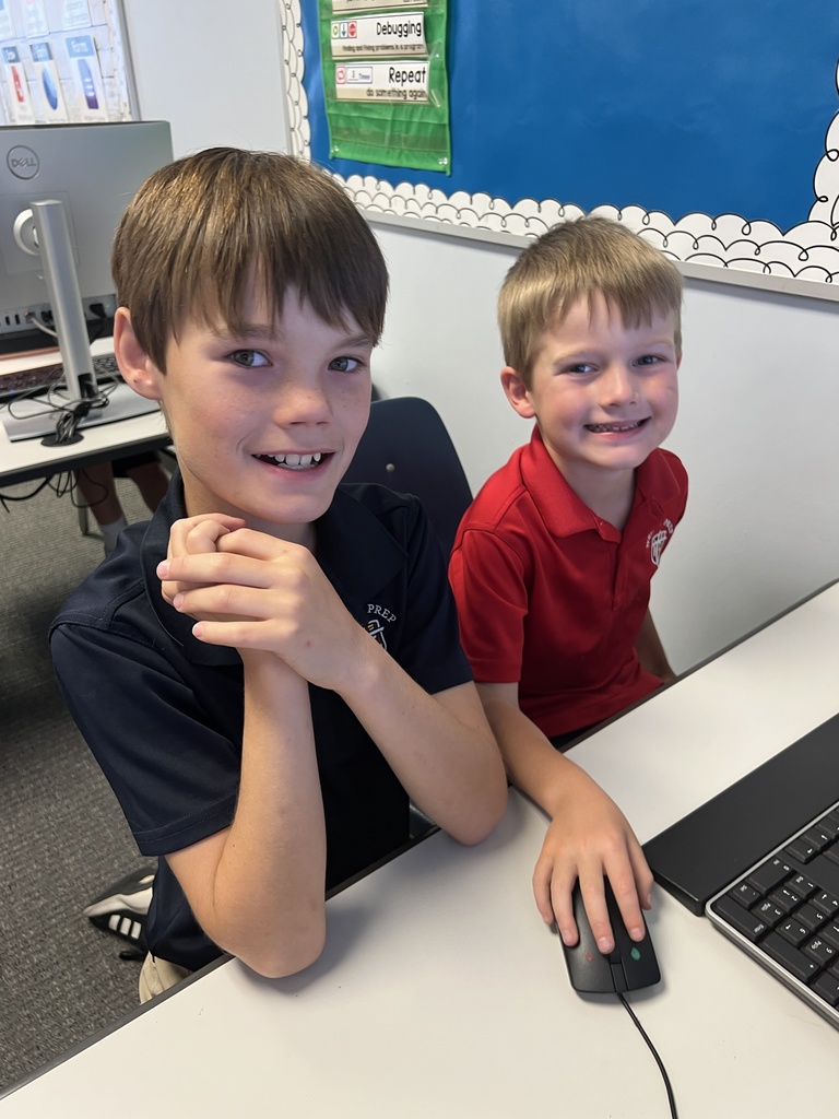 Fifth grader smiling with a younger student while they play games!