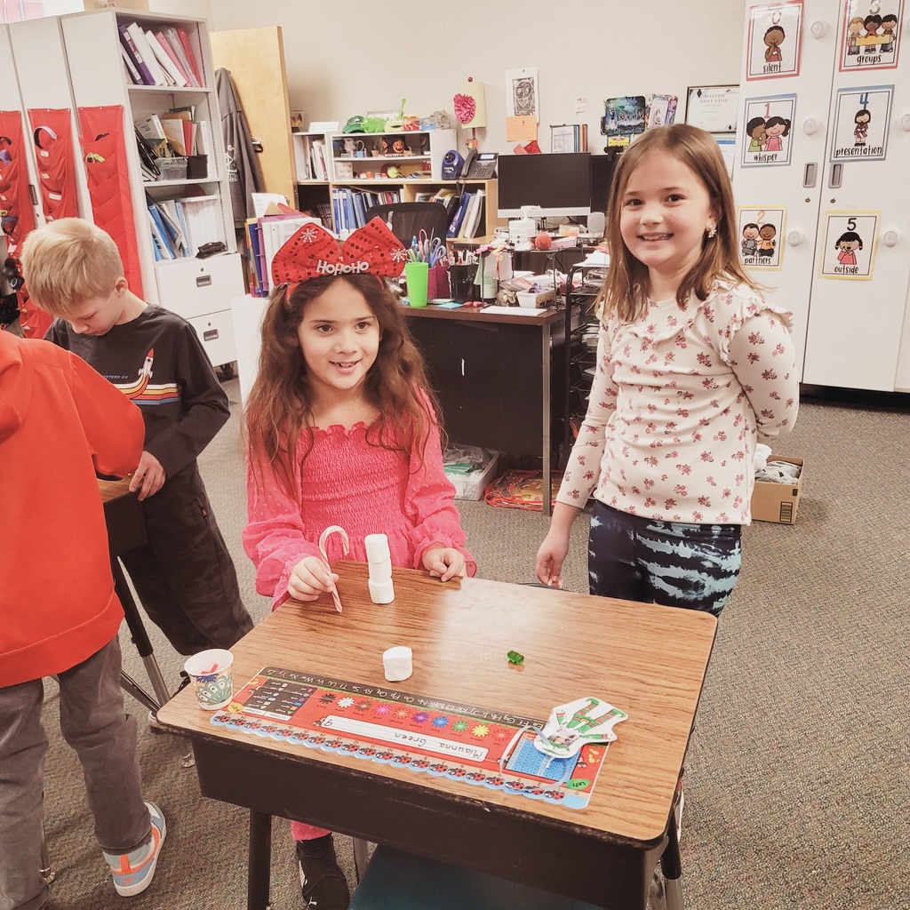 Picture of two girls standing by the three marshmallow tower they built with their candy cane.