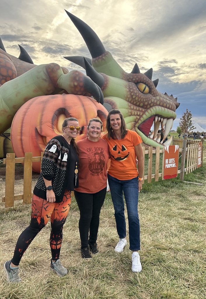A photo of 3 teachers in front of a dragon shaped walking adventure