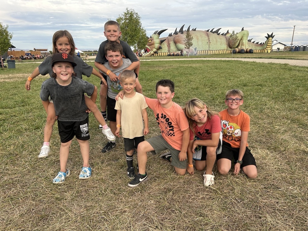 A photo of 8 students with a dragon shaped walking adventure in the background