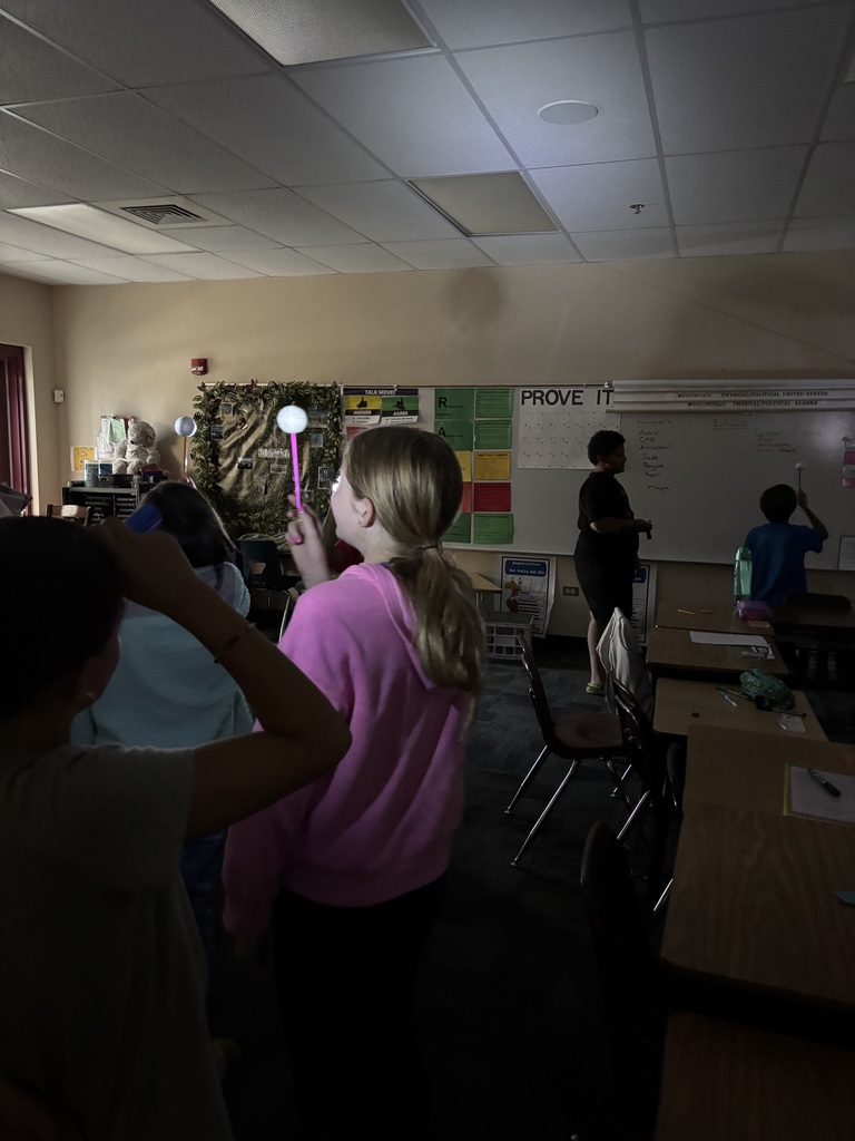 students in in dark classroom with lights on sticks