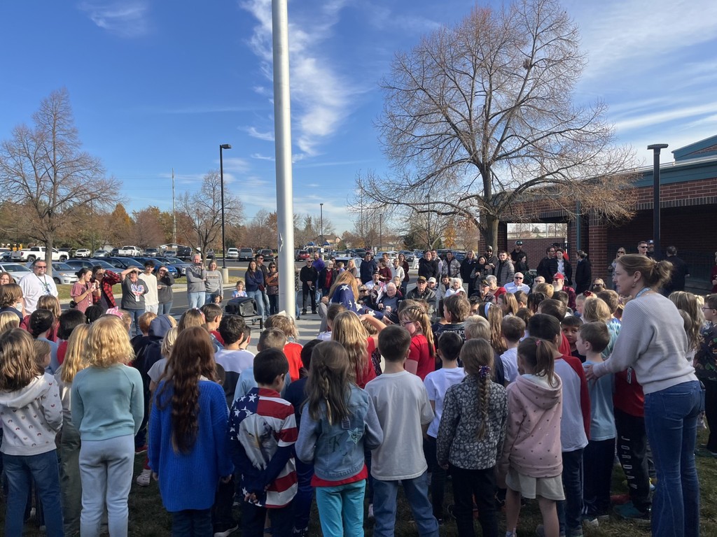 students singing the star spangled banner at the flagpole