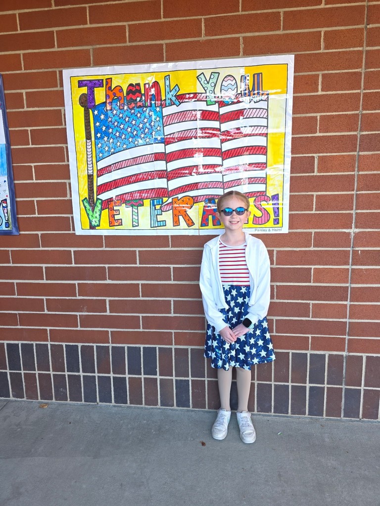 student poses at student-made veteran flag