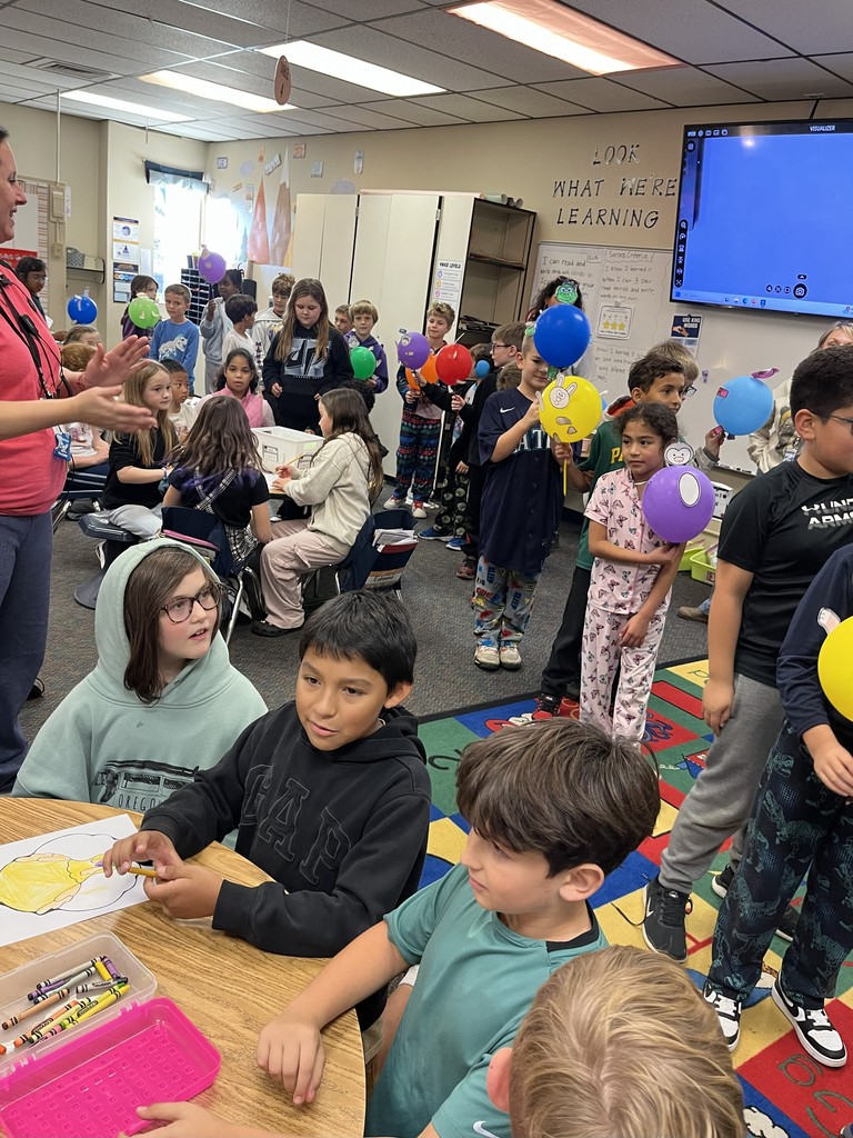 third graders parading through a first grade classroom with their Thanksgiving Day balloons
