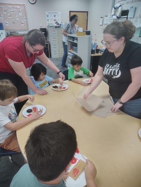 teachers helping students prepare a snack