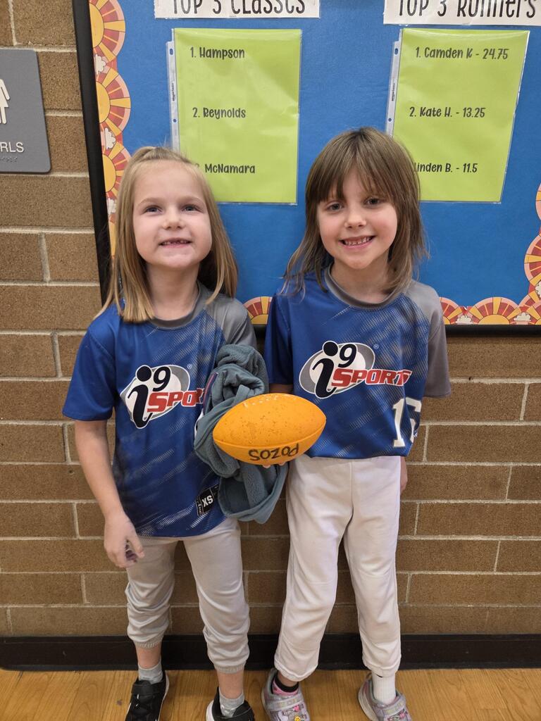 two girls in sports wear holding a football
