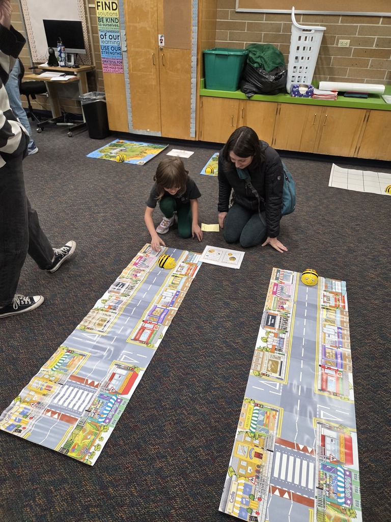 Student and mom programming BeeBots to travel on mat
