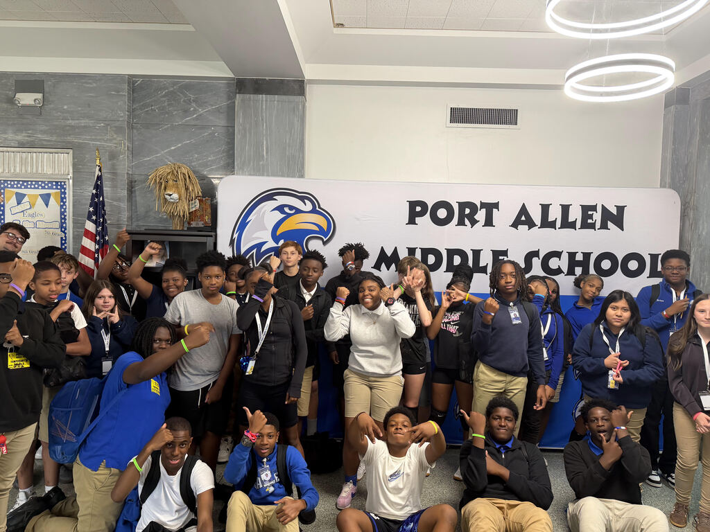 Students at Port Allen Middle School pose for a group photo. Many wear school colors and some hold up peace signs.