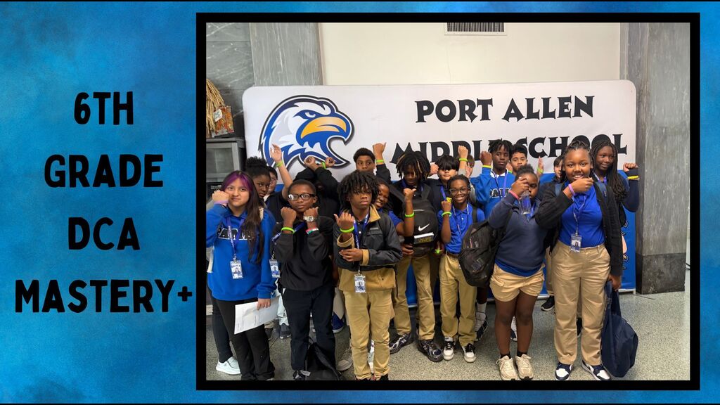 Students pose for a group photo with a school banner. They wear blue tops and pants.