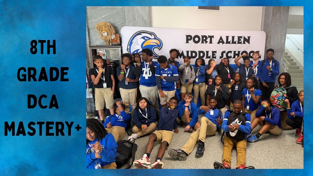 Group of students in blue shirts and sneakers pose for a photo in front of a banner.