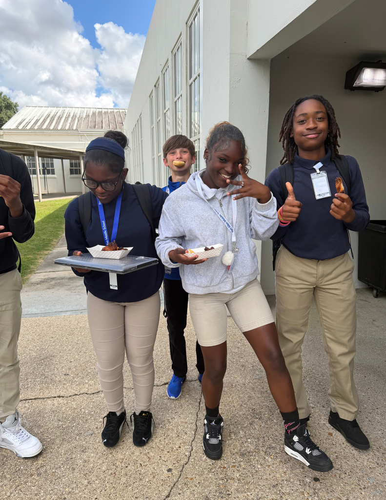 Group of students in outdoor area with building in background, all holding food and one giving a thumbs up.