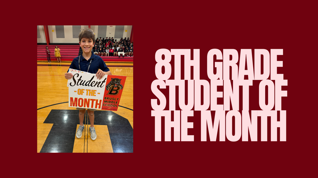 A young student in a school gym holding a sign that reads "Student of the Month".