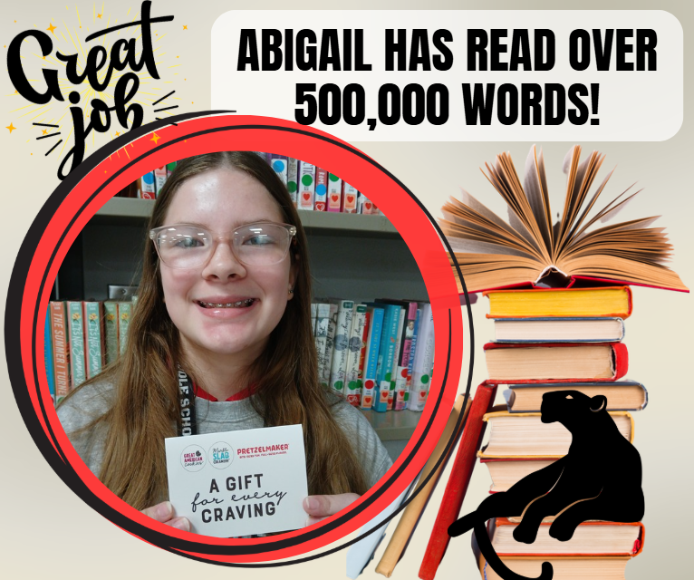 Girl holding a card saying Abigail has read over 500,000 words, surrounded by books.
