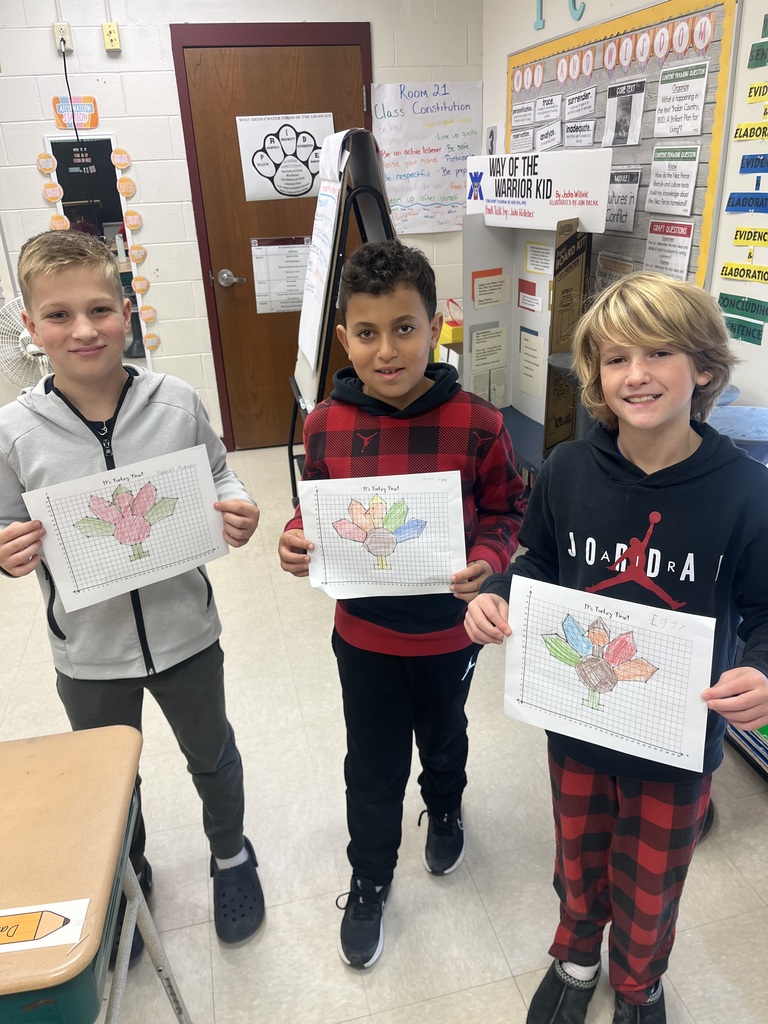 Three 5th grade boys hold up turkeys made by graphing points on a plane.