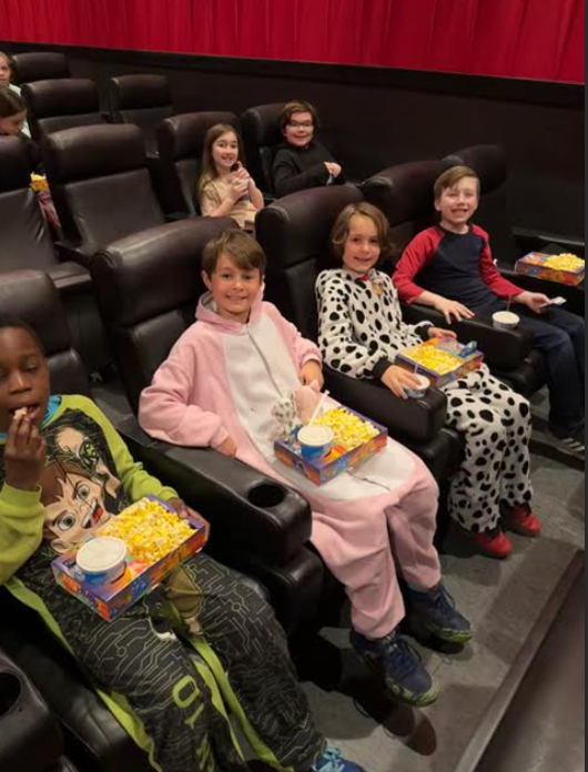 image of four boys in cozy pyjamas at a movie theater with popcorn