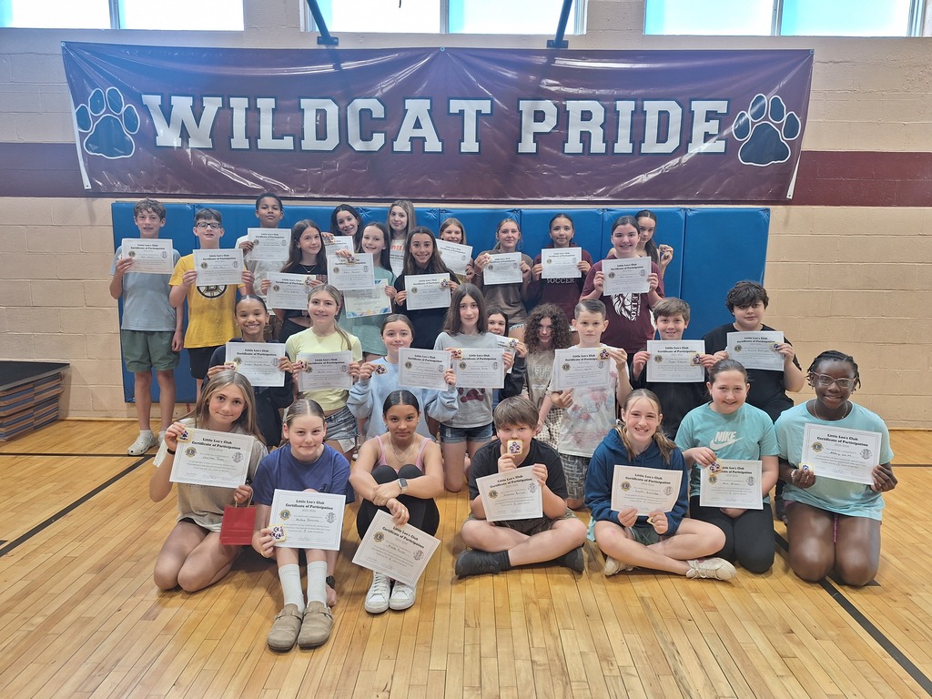 29 Howard 6th grade students pose with their Little Leos certificates in front of a banner that says "Wildcat Pride"