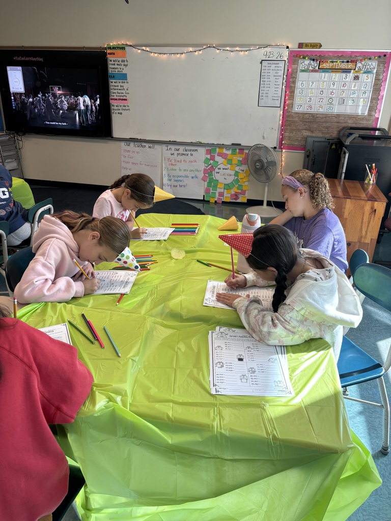 Students in party hats work on math problems at the Place Value Party!