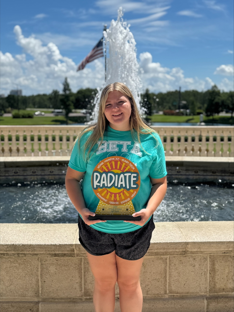 WCSSDS student with national beta trophy won during natiobnal competion, wearing beta shirt in front of a fountain