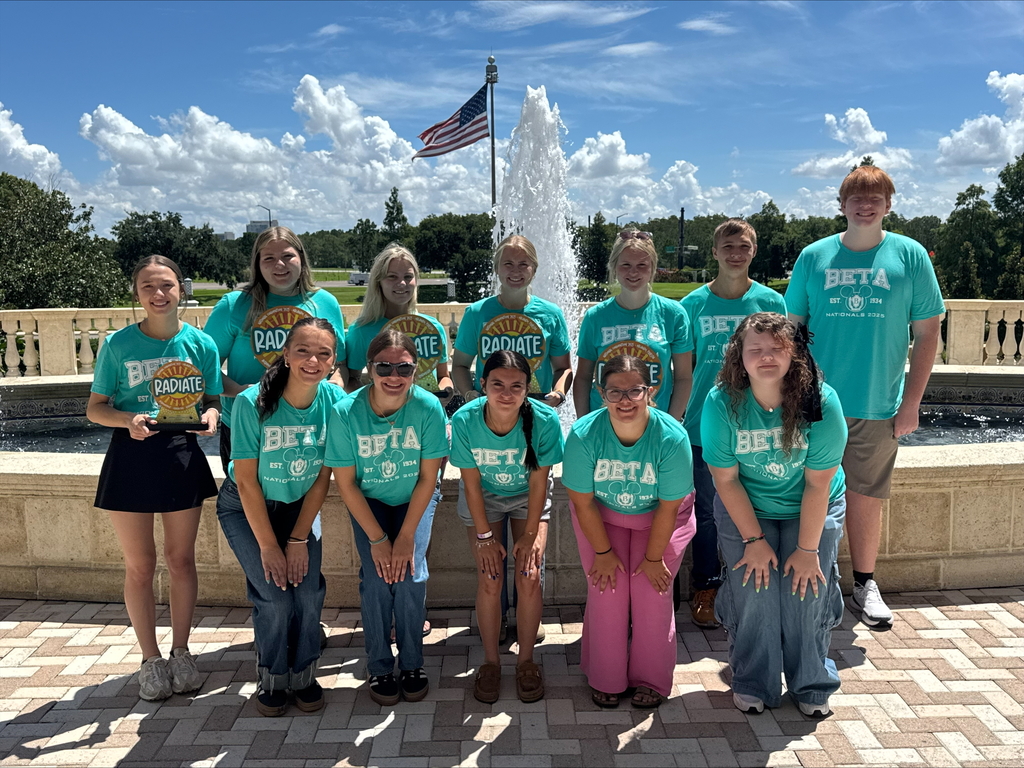 WCSSDS student with national beta trophy won during natiobnal competion, wearing beta shirt in front of a fountain