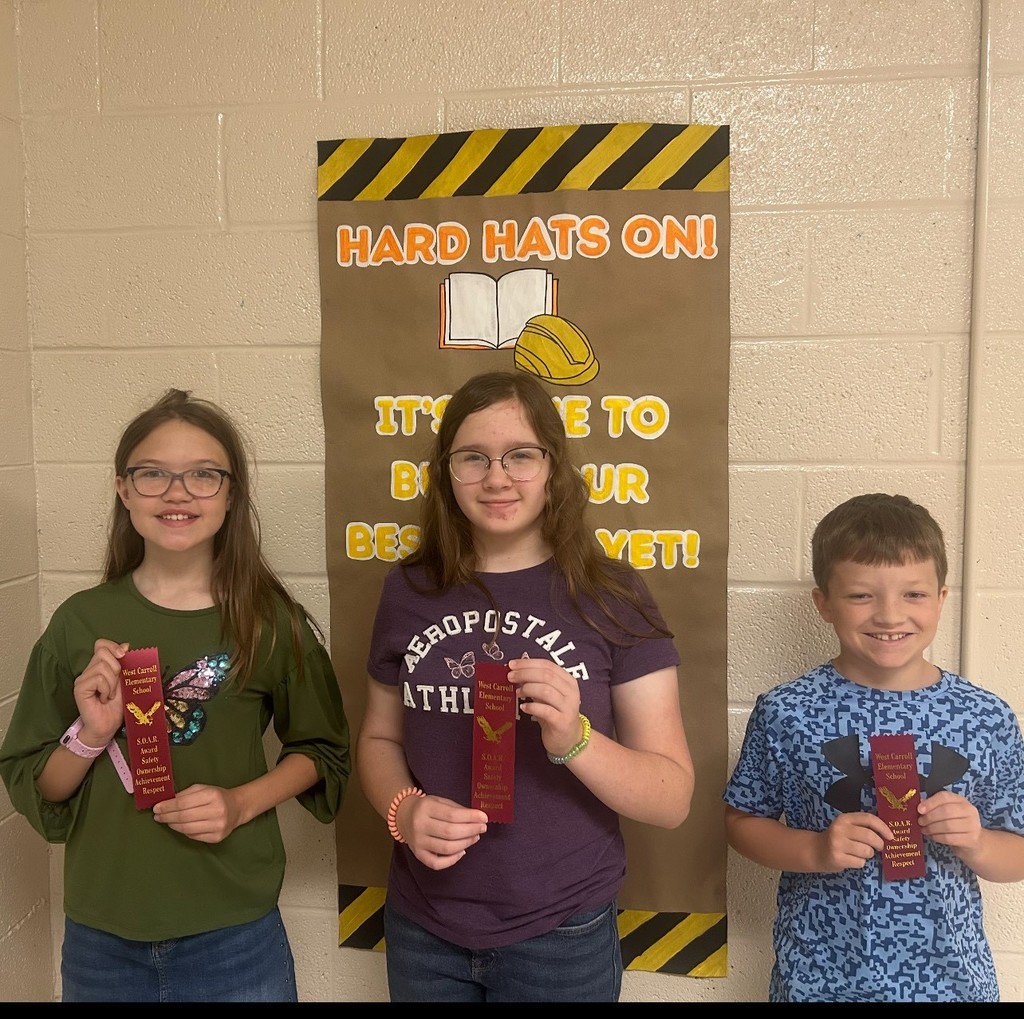 WCES SOAR Students standing with a ribbon in the lobby of school