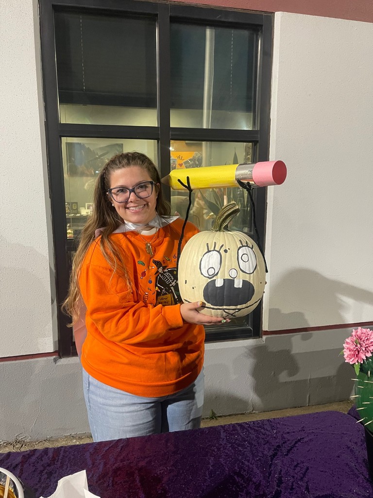Pumpkin contest winner with cute pumpkin decorated with a pencil; girl holding pumpkin in halloween shirt
