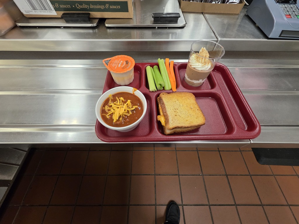 Wes Carroll High School lunch tray with themed offerings for Halloween including Witches’ Brew Chili, Gouled Cheese Sandwiches, Witch Finger carrot and celery sticks, and Spooky Pudding Cups!