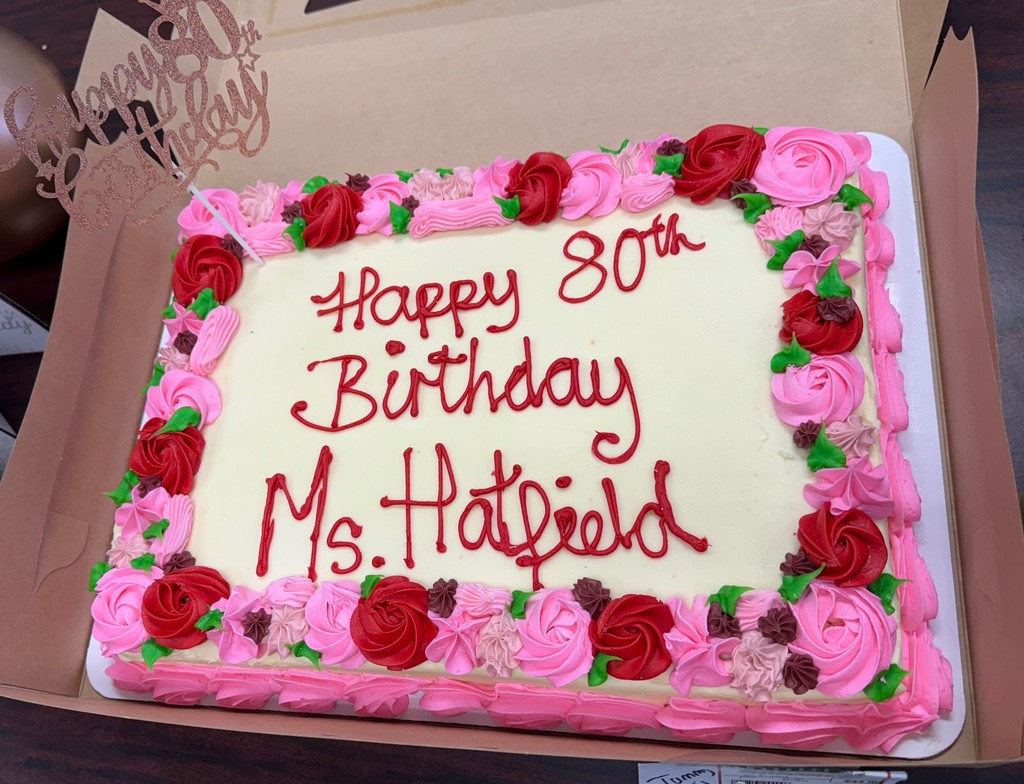 Birthday cake with "Happy 80th Birthday Ms. Hatfield" piped on top with accenting pink and red iced roses. 