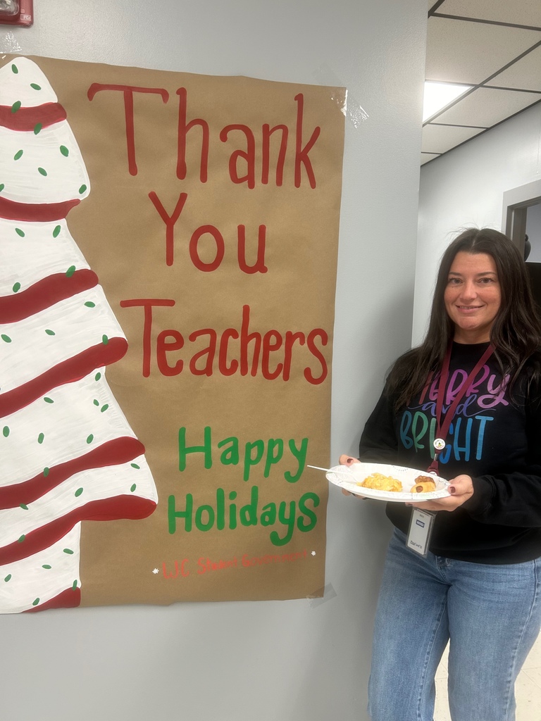 Assistant Principal, Leslie Booker, posed beside "Thank you teachers, Happy Holidays" poster