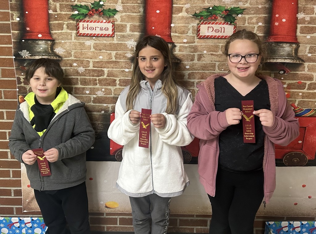 WCES SOAR students 13 and 14 standing with ribbons and in front of christmas backdrop