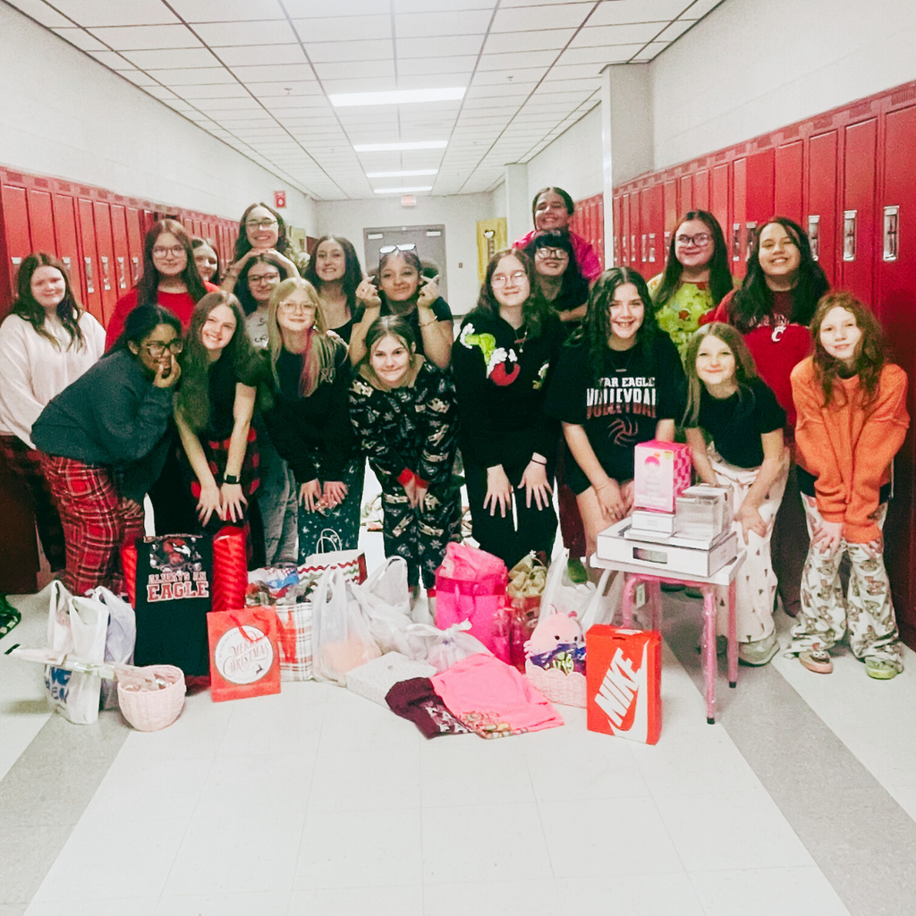 wc volleyball players standing in hallway in front of gifts donated to the angel tree
