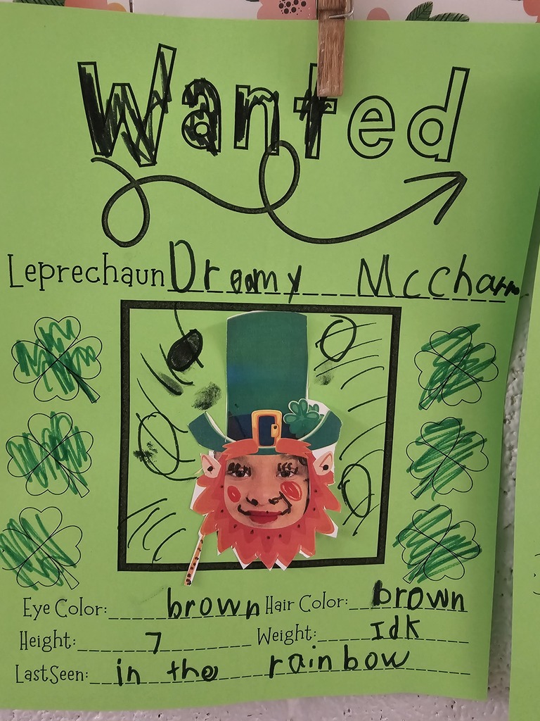 wcp student with leprechaun hat and beard for their own leprechaun writing page describing with adjectives and physical traits like eye color, hair, height, student writing illegible