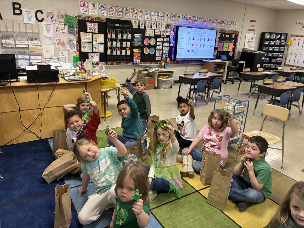 Mrs Sherrys students showingwhat they caught in the leprechaun traps created in class while sitting on the rainbow rug