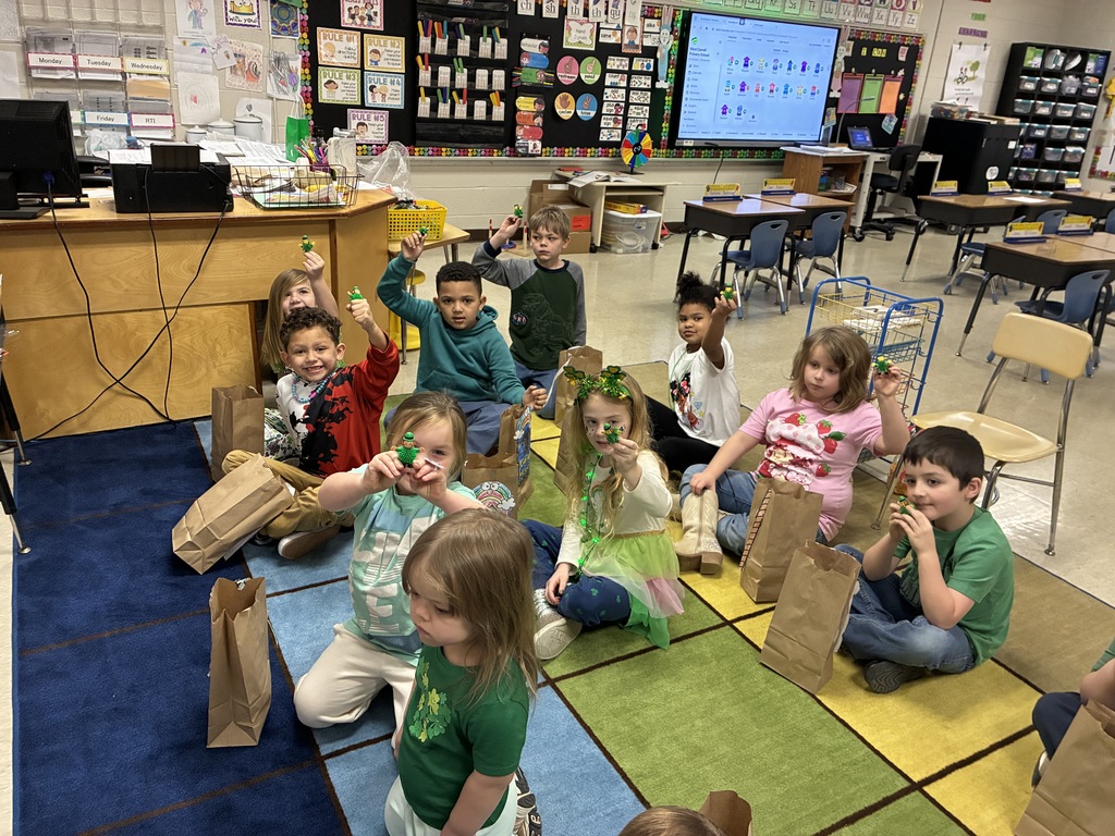 Mrs Sherrys students showingwhat they caught in the leprechaun traps created in class while sitting on the rainbow rug