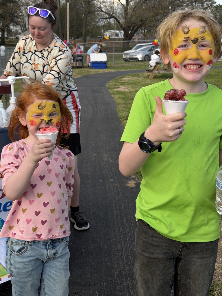 elementary students with painted character faces, enjoying a snowcone at the track during the school's math carnival.