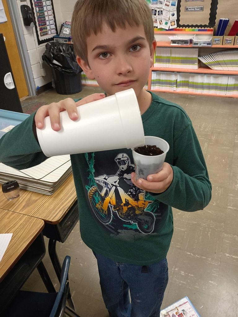 west carroll student holding cups of soil and seeds as they begin learning about plants