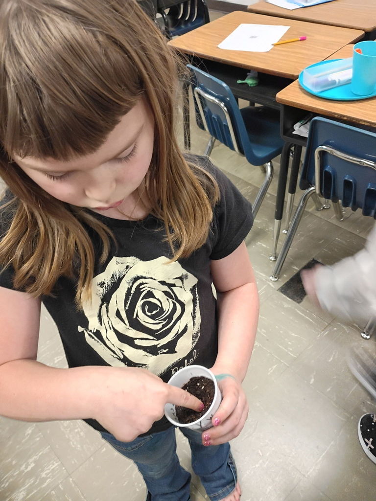 west carroll student holding cups of soil and seeds as they begin learning about plants