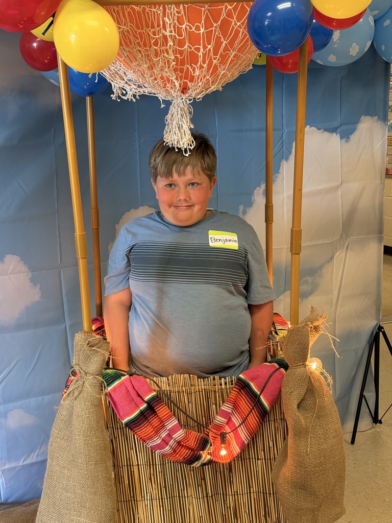second grader posing with balloon photo area