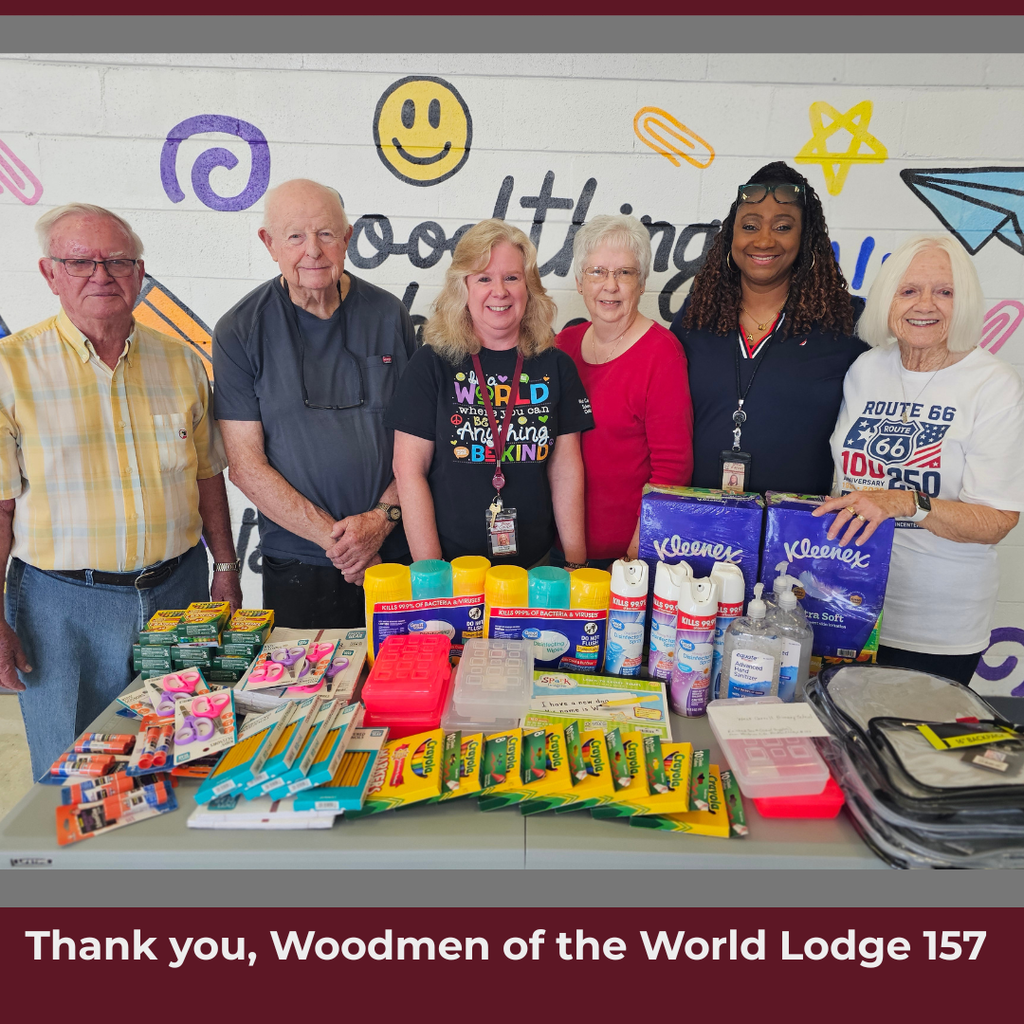 Six adults presenting school supplies to school with supplies on table in front