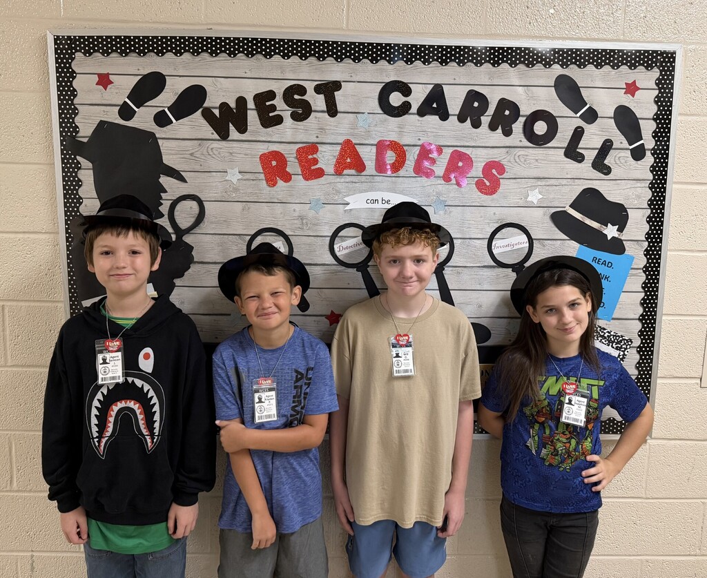 west carroll elementary students wearing detective hats, standing infront of bulletin board being recognized for reading books for competition