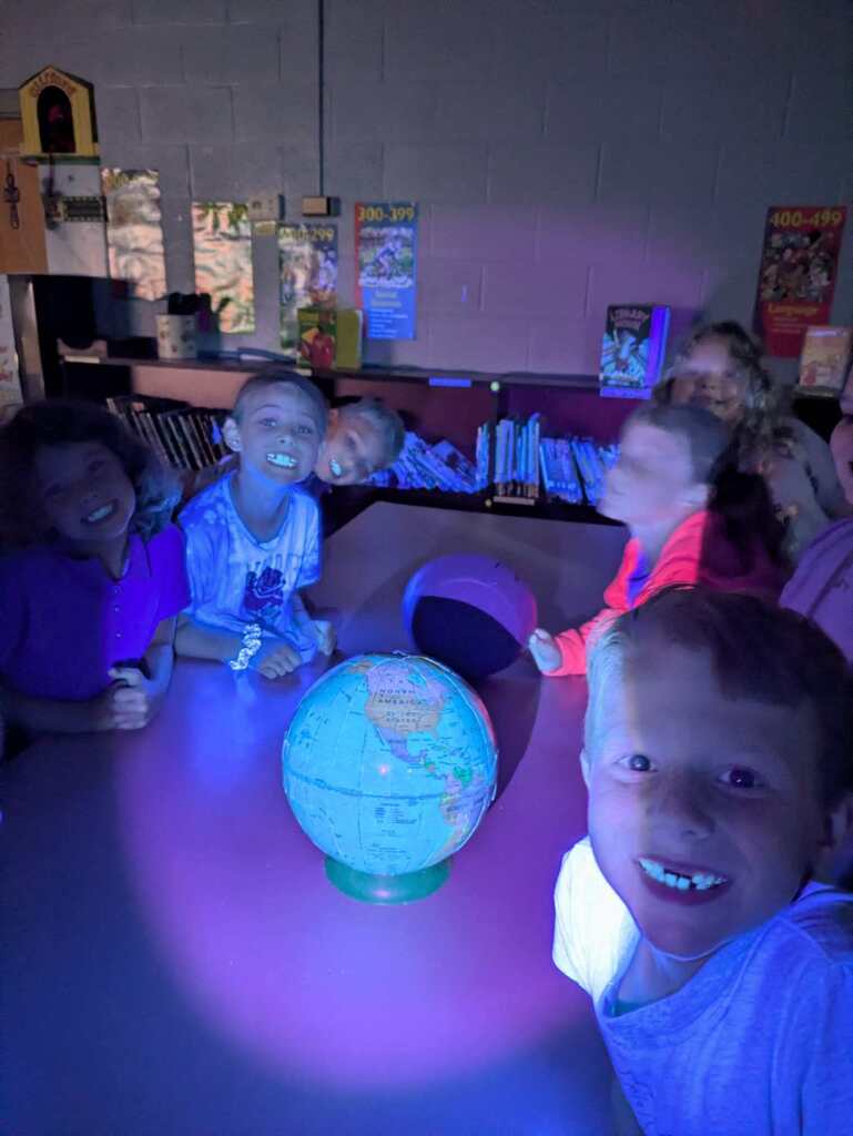 west carroll primary students studying lunar eclipses with black lights and shadows five students smiling