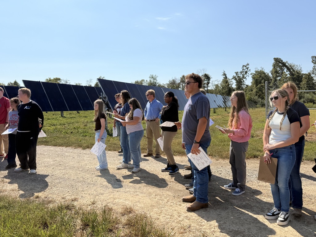 West Carroll students stand alongside rows of solar panels while learning about solar energy production and the operation of the Trezevant Solar Farm.