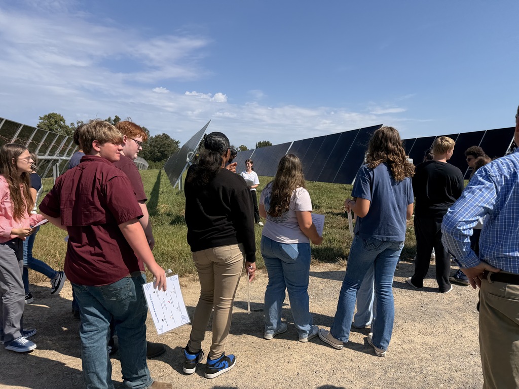 West Carroll students tour the Trezevant Solar Farm, listening to a presentation while standing among rows of large solar panels.