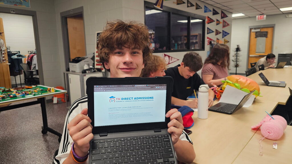 A smiling West Carroll senior holds up her laptop displaying the TN Direct Admissions website with a large “YOU’RE IN!” message after receiving a direct admission offer.
