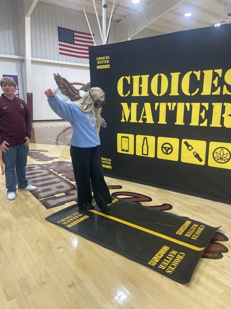 A West Carroll student participates in a balance and coordination activity while wearing impairment-simulation goggles in front of the Choices Matter display.