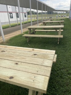 Newly built wooden picnic tables made by West Carroll Ag students are lined up outside the school, ready to be used as an outdoor lunch area for seniors.