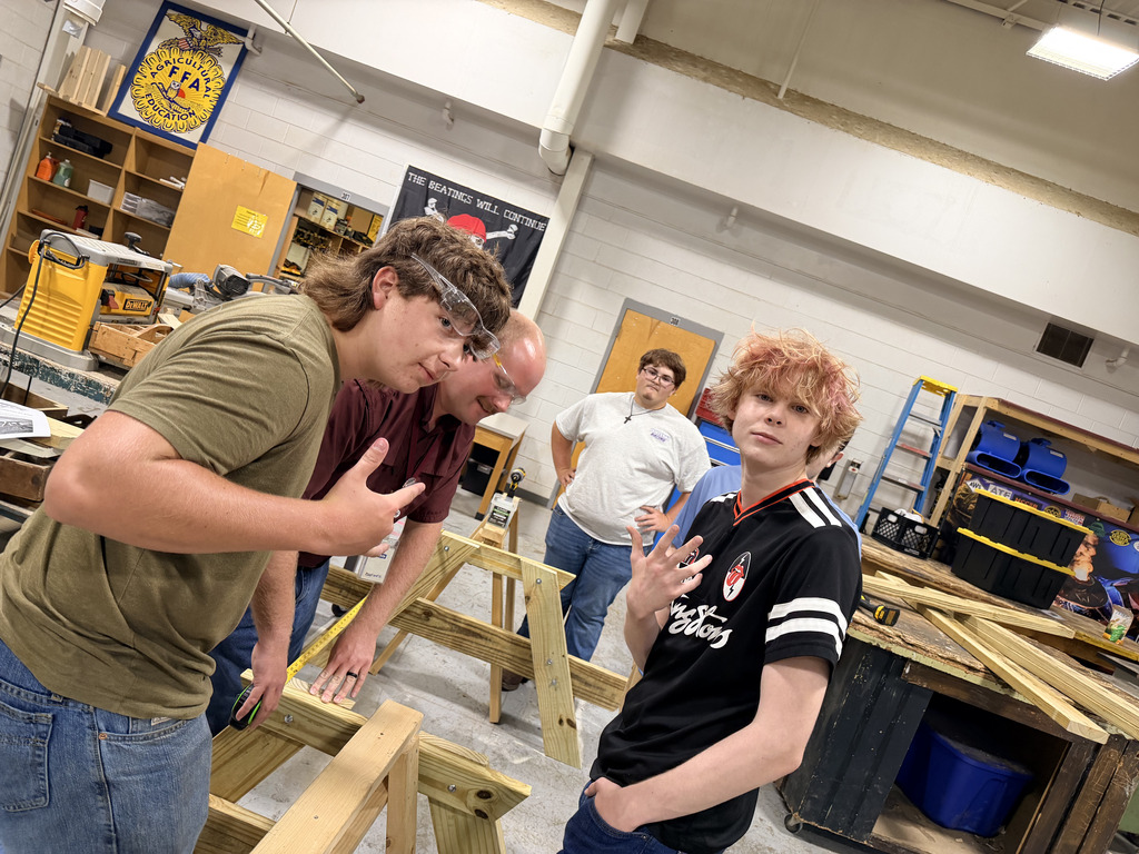 West Carroll Ag students work with Mr. Rogers to measure and assemble wooden picnic tables in the school shop.