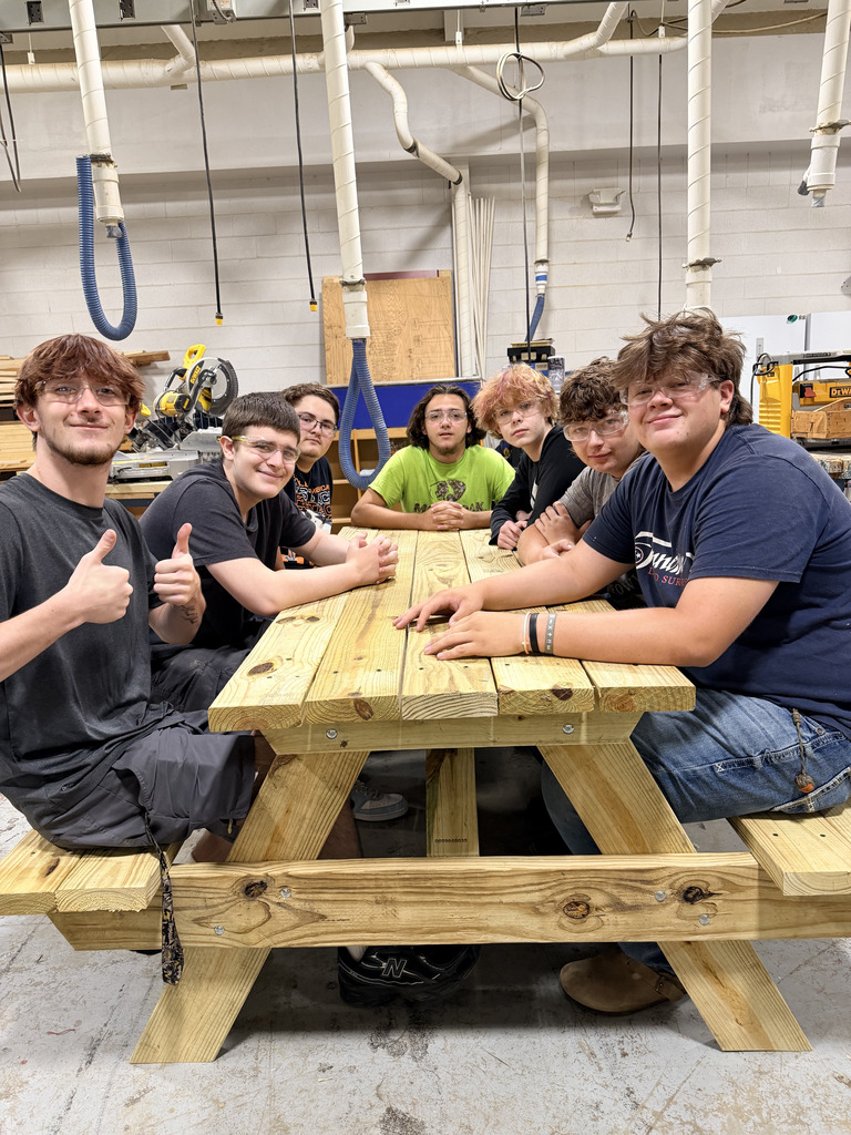 A group of West Carroll Ag students sit around one of the wooden picnic tables they built for the new outdoor senior lunch area.