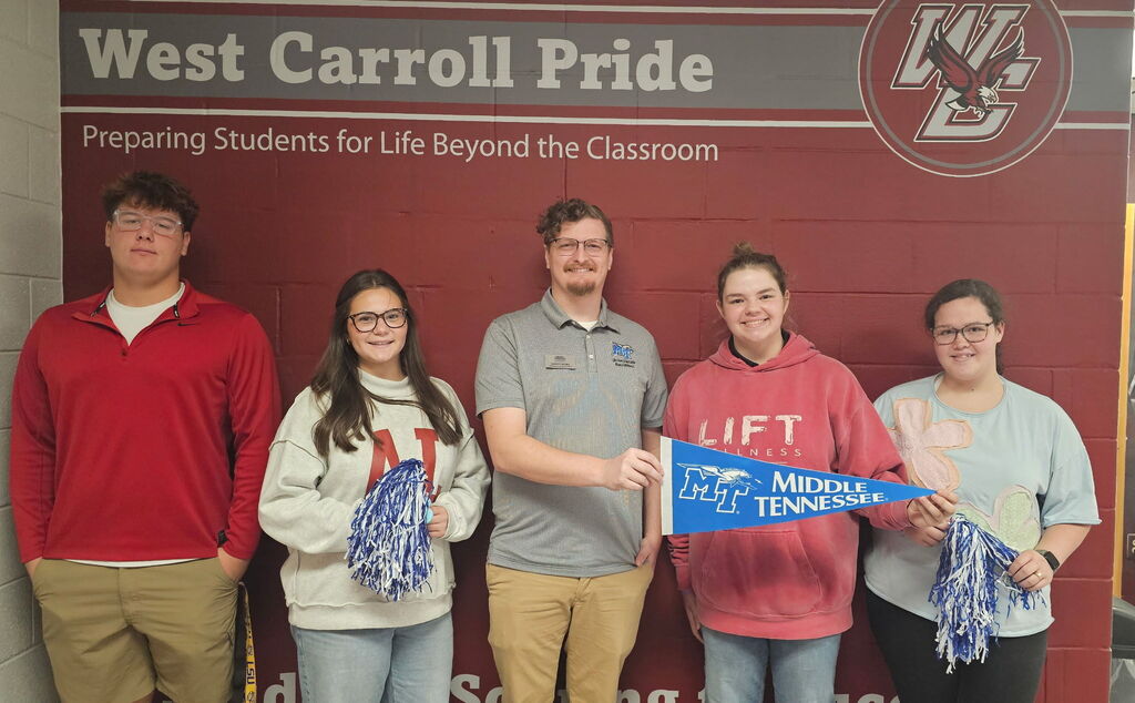 West Carroll Class of 2014 graduate and MTSU Admissions Counselor Garrett McNeil stands with four West Carroll Senior Class Officers in front of the school’s West Carroll Pride display. Garrett and one student hold a blue Middle Tennessee State University pennant, while two students hold blue and white pom-poms.