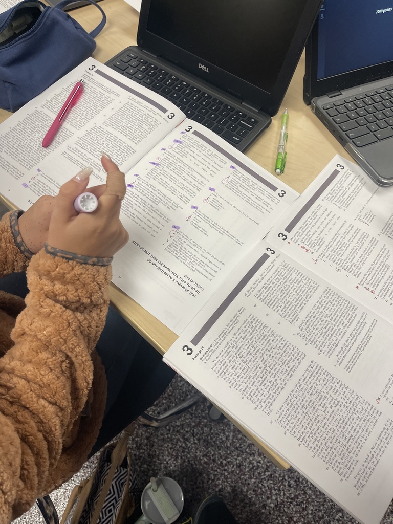 Close-up of a student working through marked ACT practice test pages during West Carroll’s ACT Bootcamp, with laptops and additional testing materials on the table.