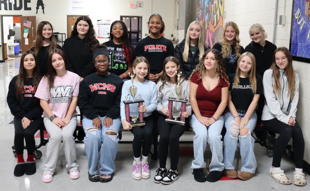 Cheerleaders holding two trophies